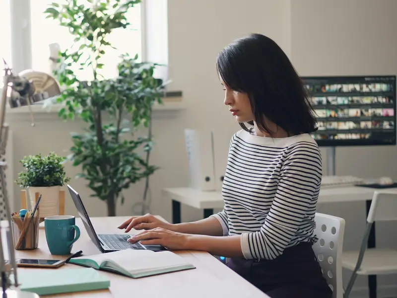 Contabilă Bilanza lucrând la laptop, într-un birou luminos cu plante